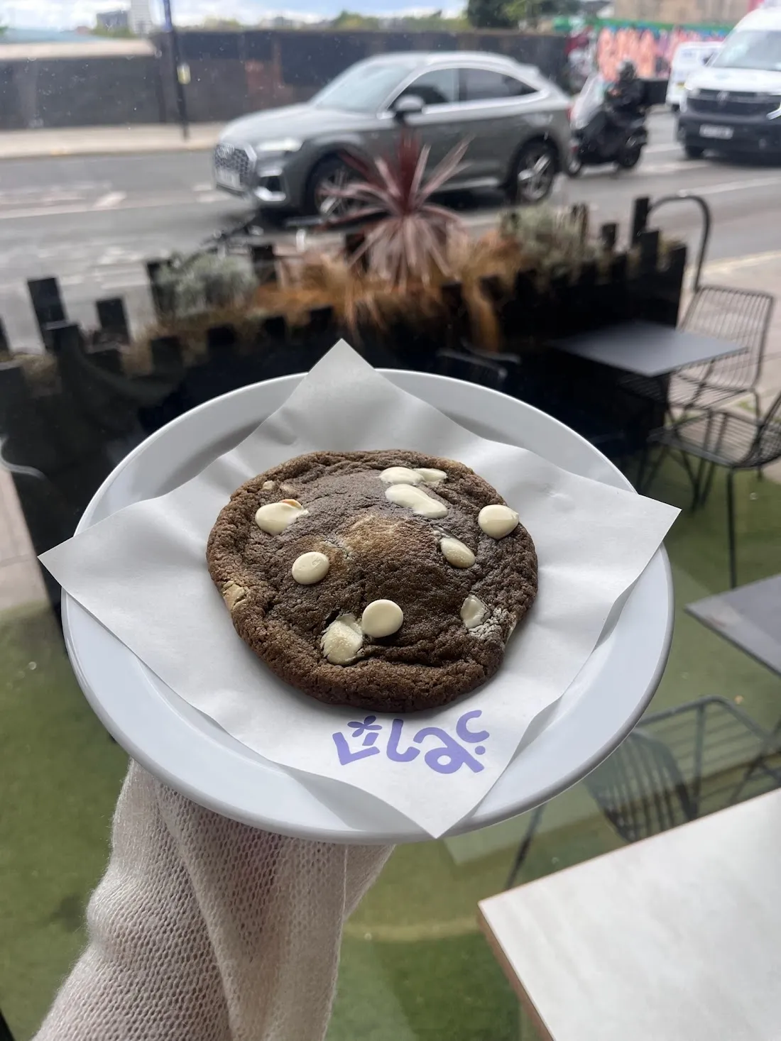 A cookie on a plate held up outside a café
