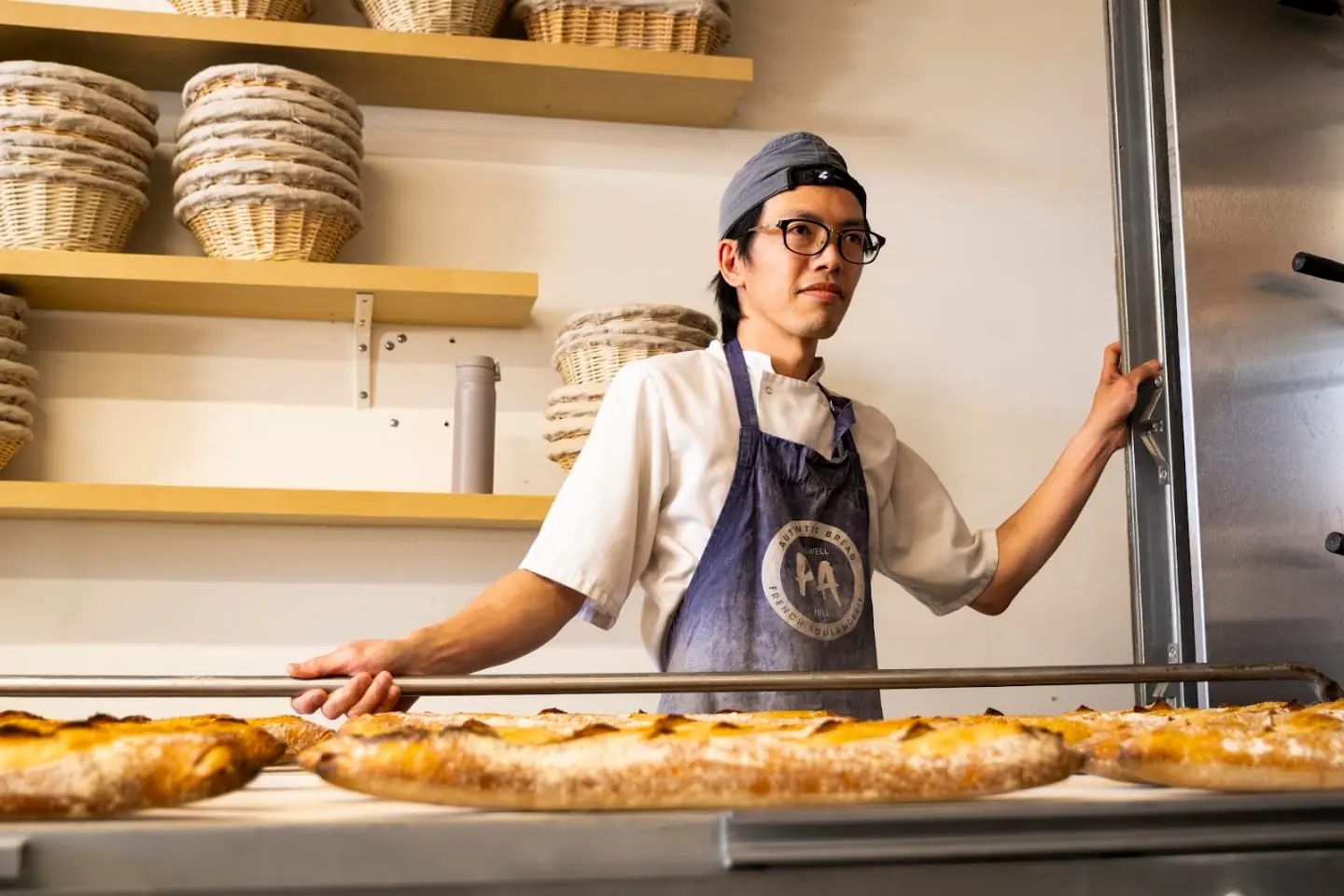 A baker holding a long loaf in the bakery