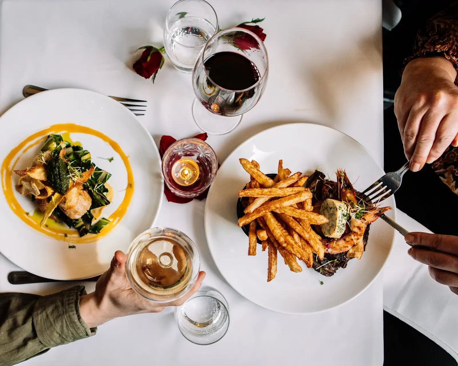An overhead view of a bistro table with plates, frites and wine