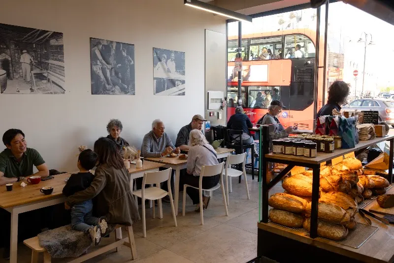 A busy neighbourhood café with a bus passing outside