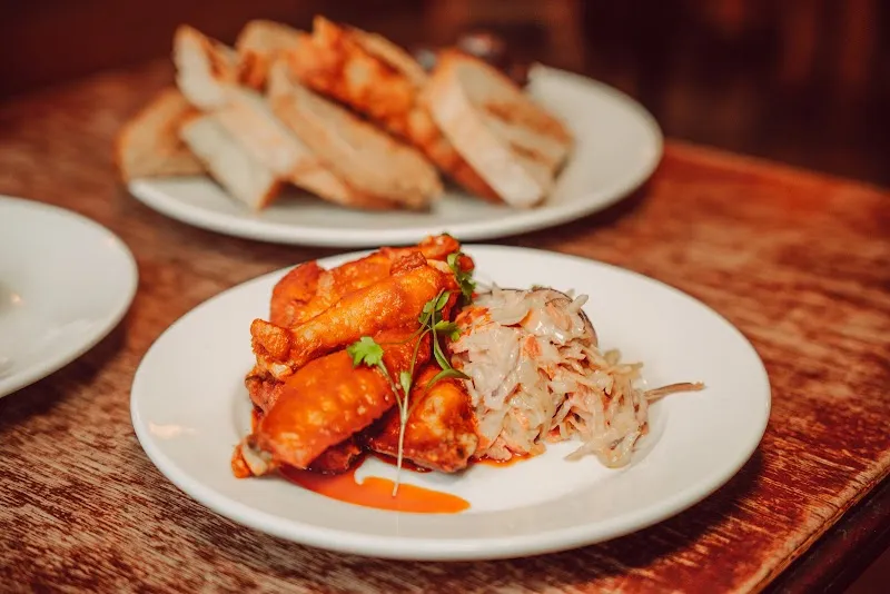 A plate of chicken wings with bread on a pub table