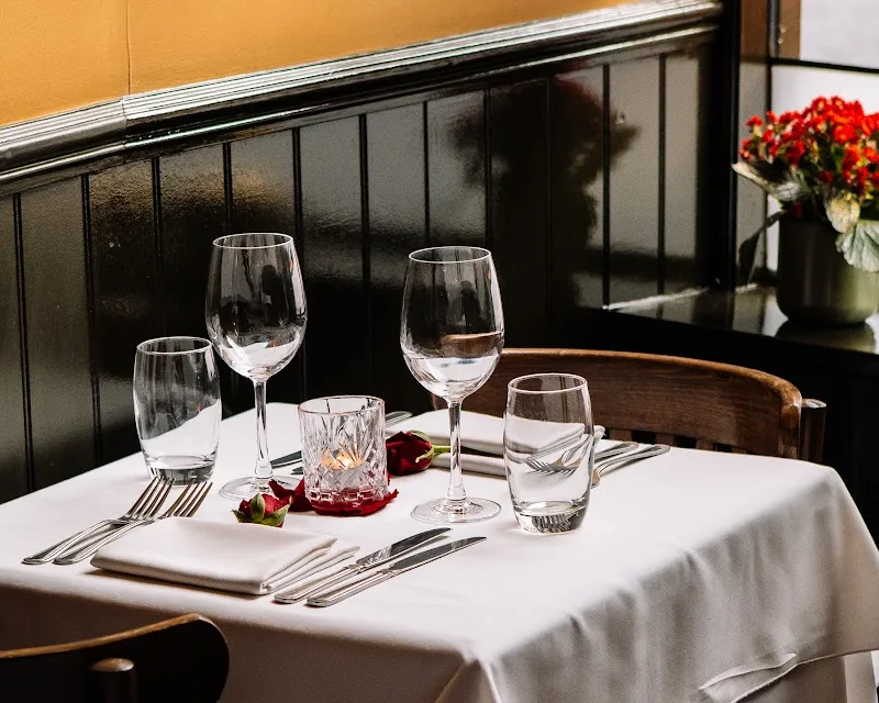 A dining table laid with white linen and wine glasses