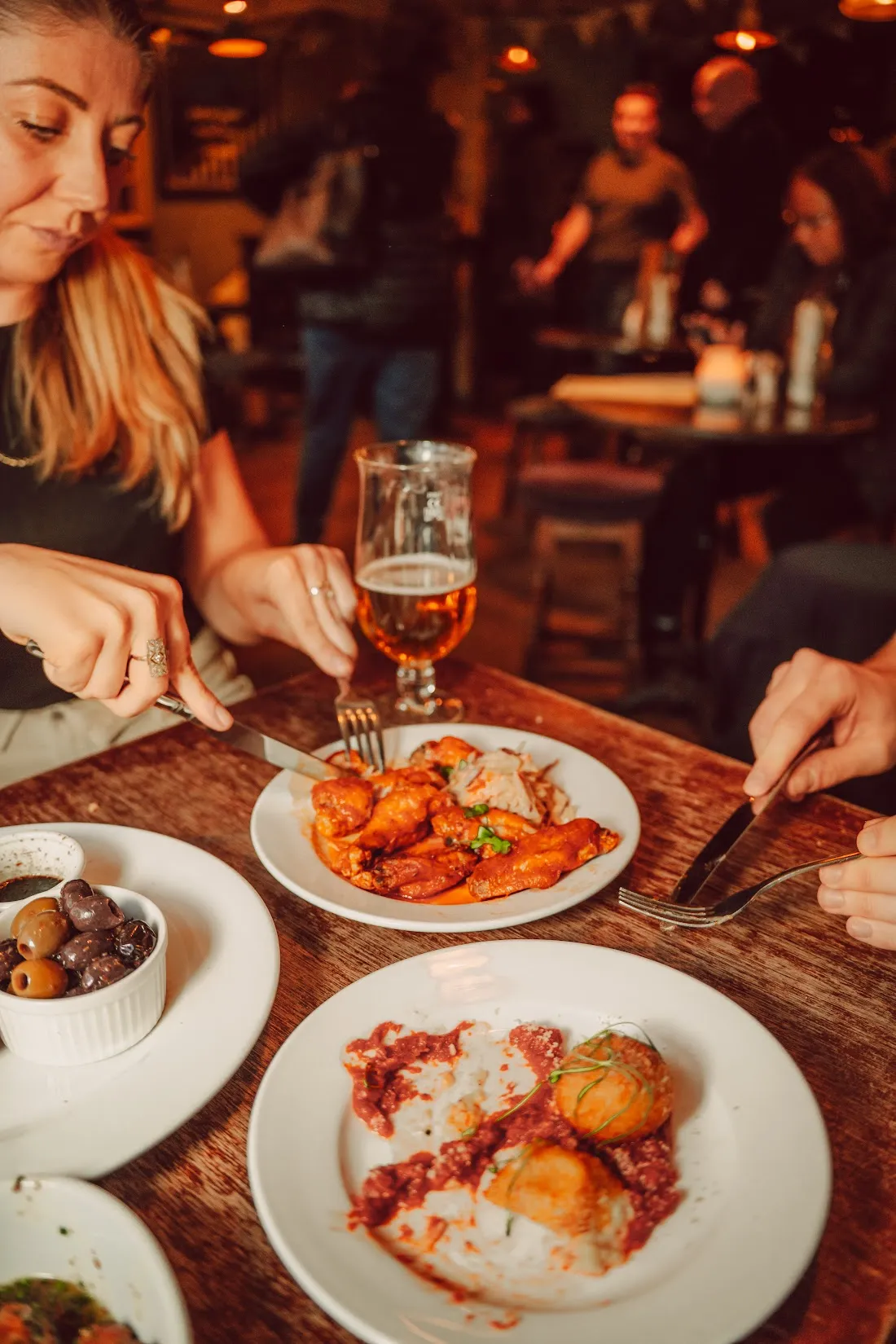 Friends sharing plates of food and drinks at a pub table