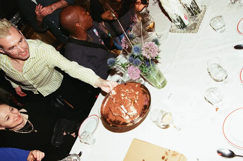 Guests reaching for a sharing dish at a supper club