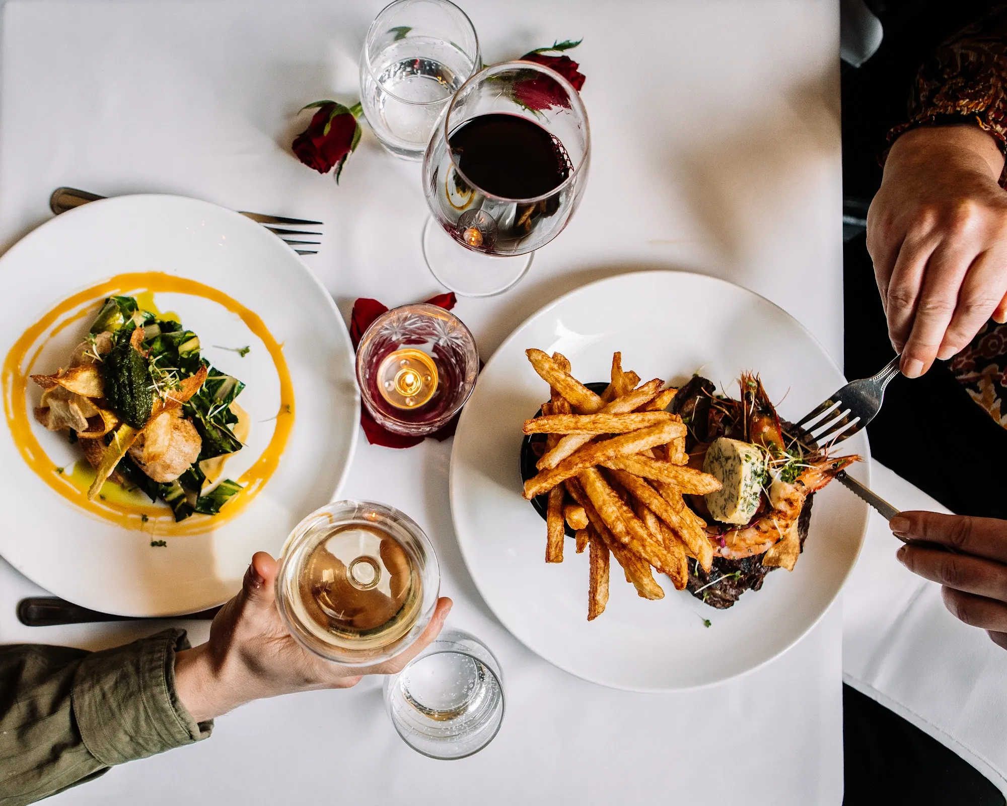 An overhead view of a bistro table with plates, frites and wine