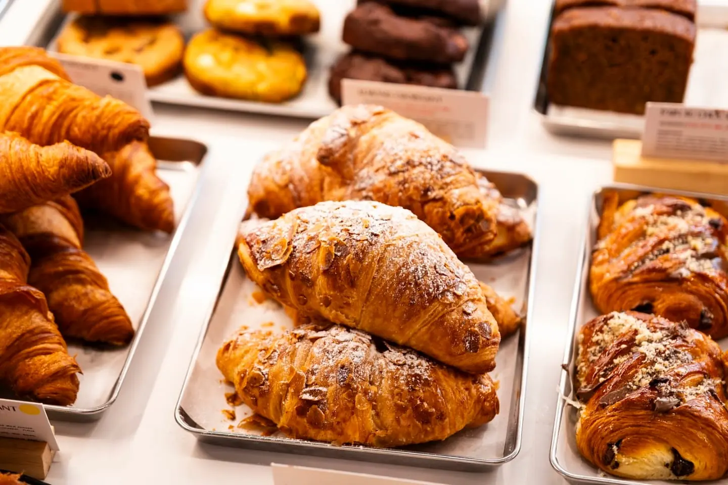 Trays of golden croissants and pastries on a counter