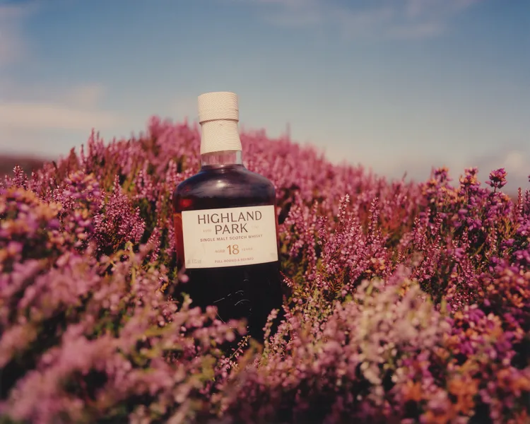 A whisky bottle standing in a field of purple heather