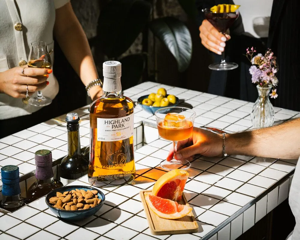 A bottle of whisky and cocktails on a tiled table